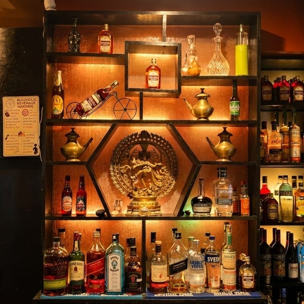 A well-stocked bar with various liquor bottles, decorative elements, and a TV screen showing sports.